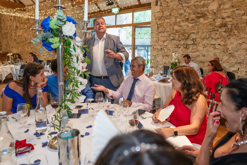 Notley Abbey Wedding photographer. Magician making guest laugh in Monk's refectory.