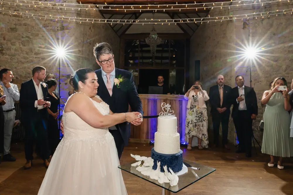 Notley Abbey Wedding photographer. Cutting the cake in monk's refectory.