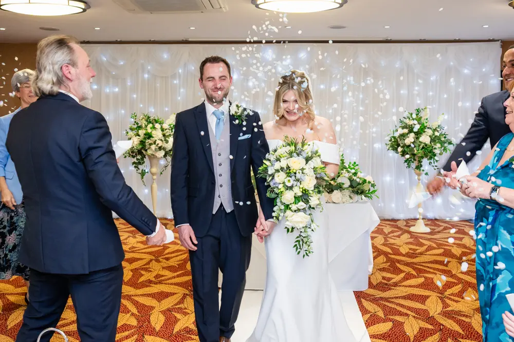 Bull Hotel wedding photography. Bride and groom walk through confetti in Bullstrode Suite.