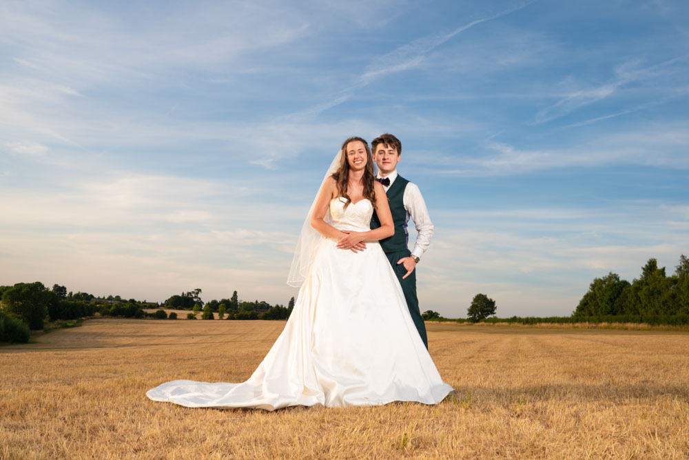 Bride and groom in field at sunset by Oxford wedding photographer.