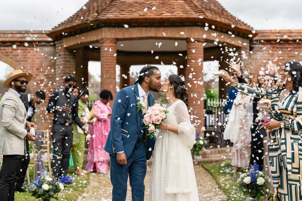 Abingdon wedding photo. Bride and groom kiss under confetti at Milton Hill House wedding.