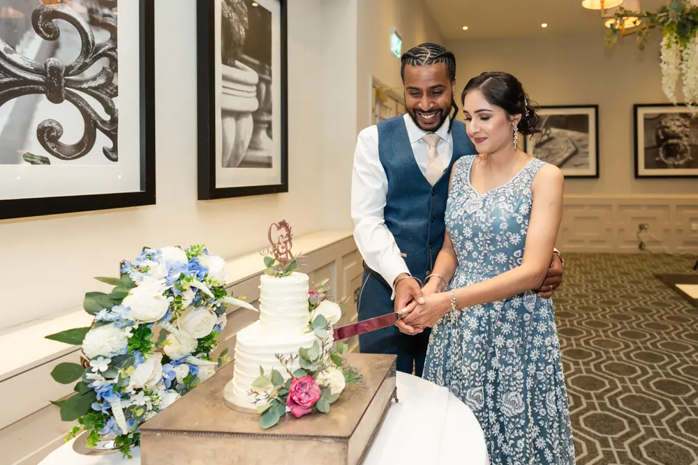 Bride and groom cutting wedding cake with Milton Hill House wedding photographer