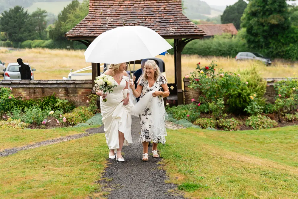 St Boltoph Bradenham wedding photography. Bride arriving for ceremony in rain.
