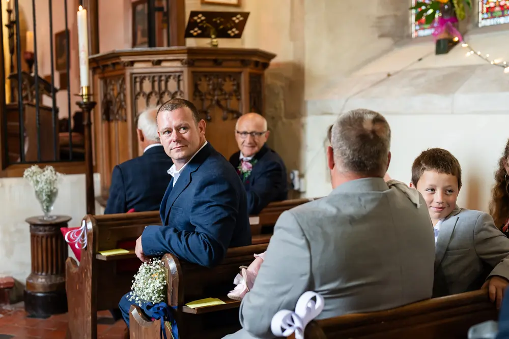 St Boltoph Bradenham wedding photography. Guests look on as bride arrives for ceremony.