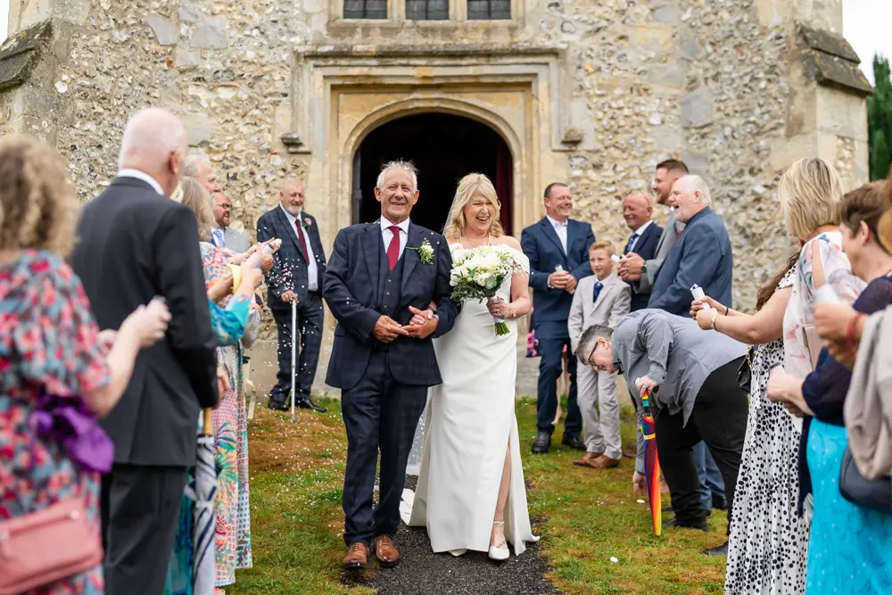 St Boltoph Bradenham wedding photography. Bride and groom in confetti tunnel leaving church.