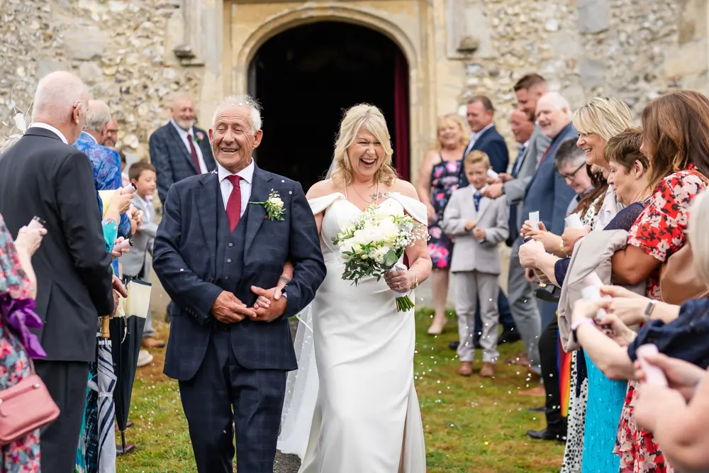St Boltoph Bradenham wedding photography. Bride and groom in confetti tunnel leaving church.
