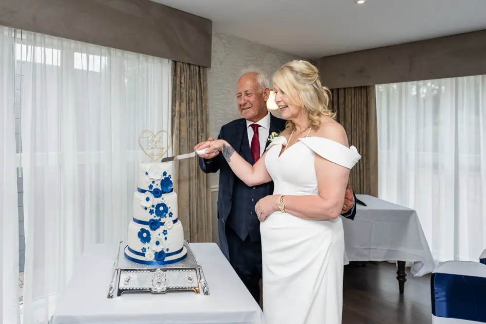 Bride and groom cut cake at their Lambert Arms wedding reception after a church ceremony at St Boltoph Bradenham