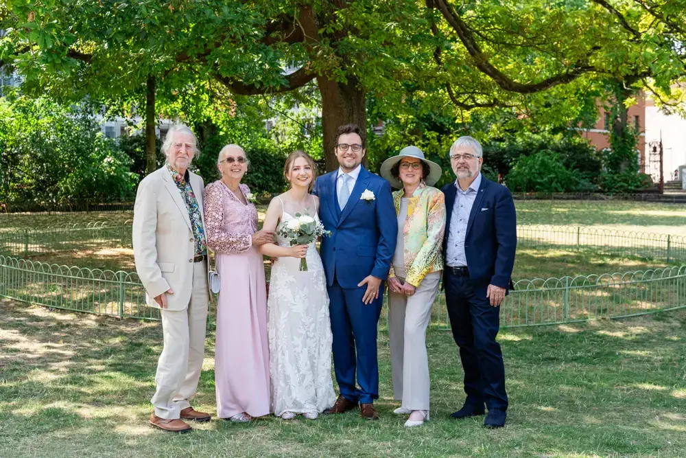 Bride and groom with guests under tree. Forbury Gardens wedding photos. Reading, Berkshire.