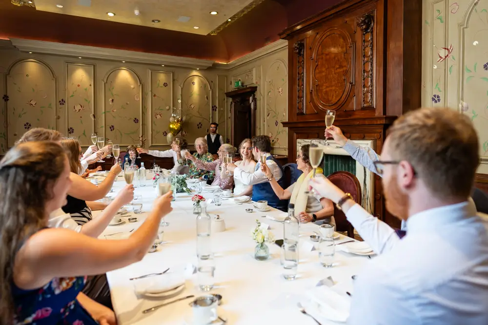bride and groom toast each other at wedding breakfast. Roseate wedding photographer in Reading.