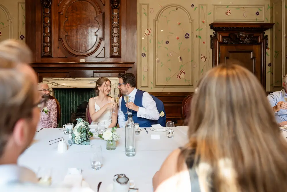 bride and groom toast each other at wedding breakfast. Roseate wedding photographer in Reading.