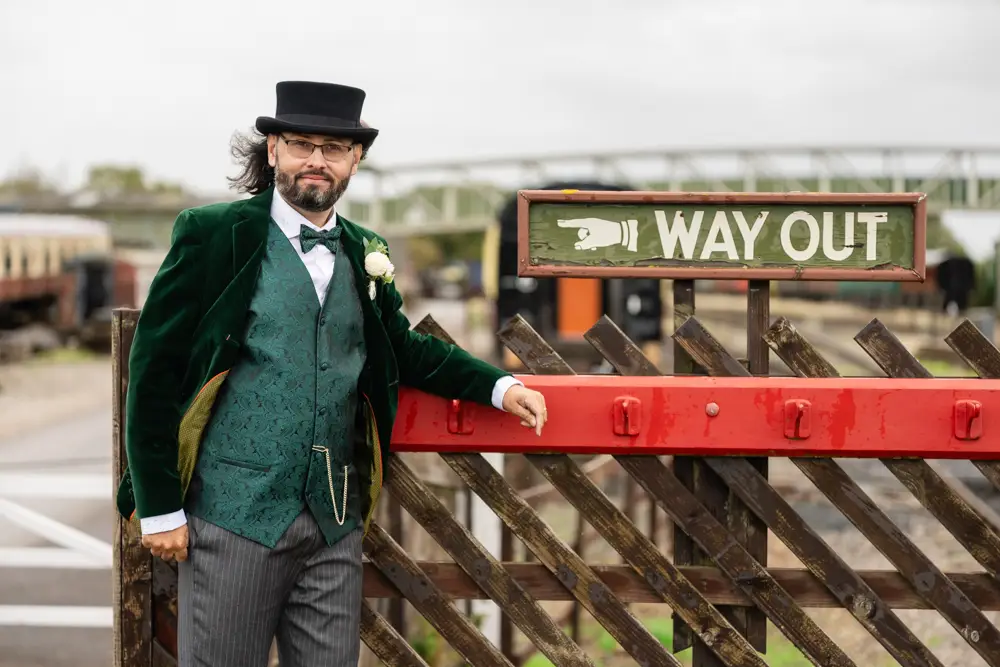Buckinghamshire Railway Centre Wedding Photographer. Groom next to way out sign on platform.