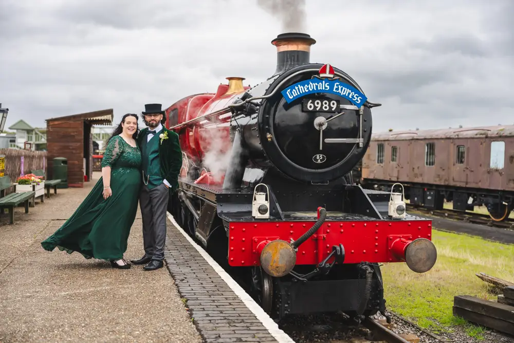 Buckinghamshire Railway Centre Wedding Photographer. Bride and groom next to red steam train in Storm Amy.