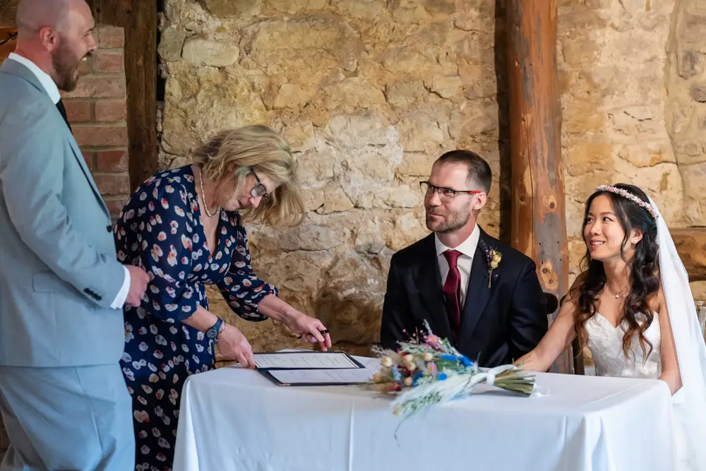 Notley Tythe Barn Wedding Photography. Bride and groom during wedding ceremony in barn.