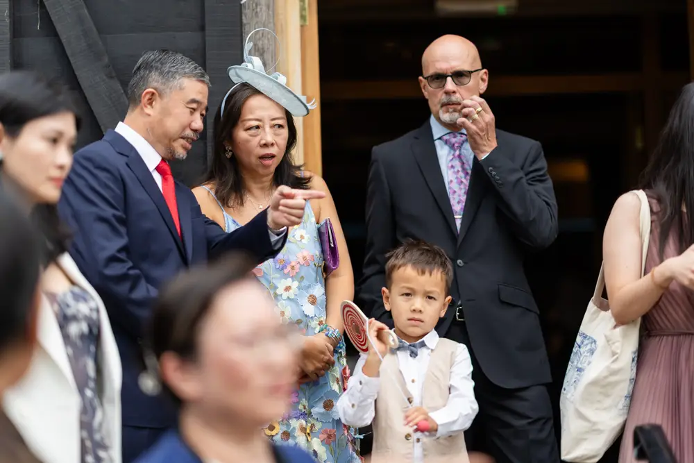 Notley Tythe Barn Wedding Photography. Wedding guests chatting outside barn.
