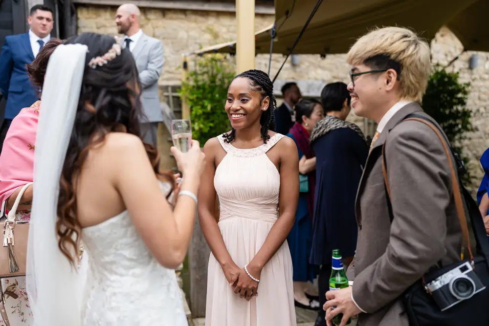 Notley Tythe Barn Wedding Photography. Wedding guests chatting outside barn.