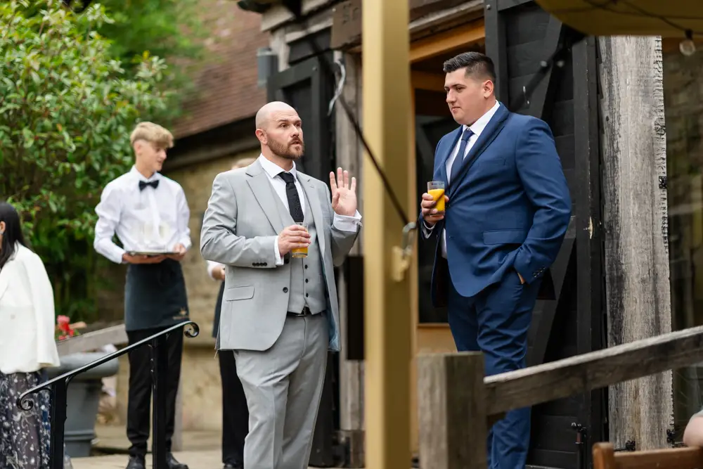 Notley Tythe Barn Wedding Photography. Wedding guests chatting outside barn.