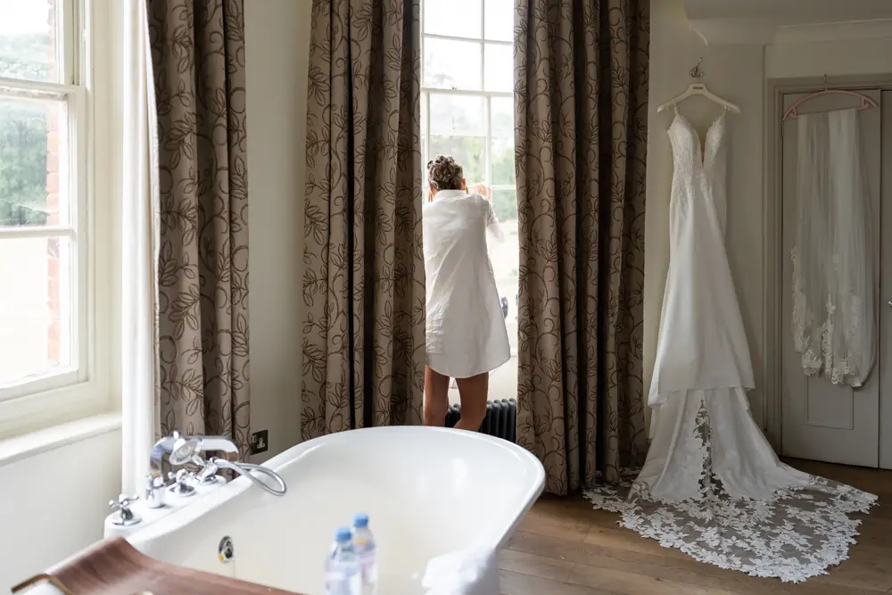 Stoke Place wedding photographer. Bride looking out of window in Alexandra suite.