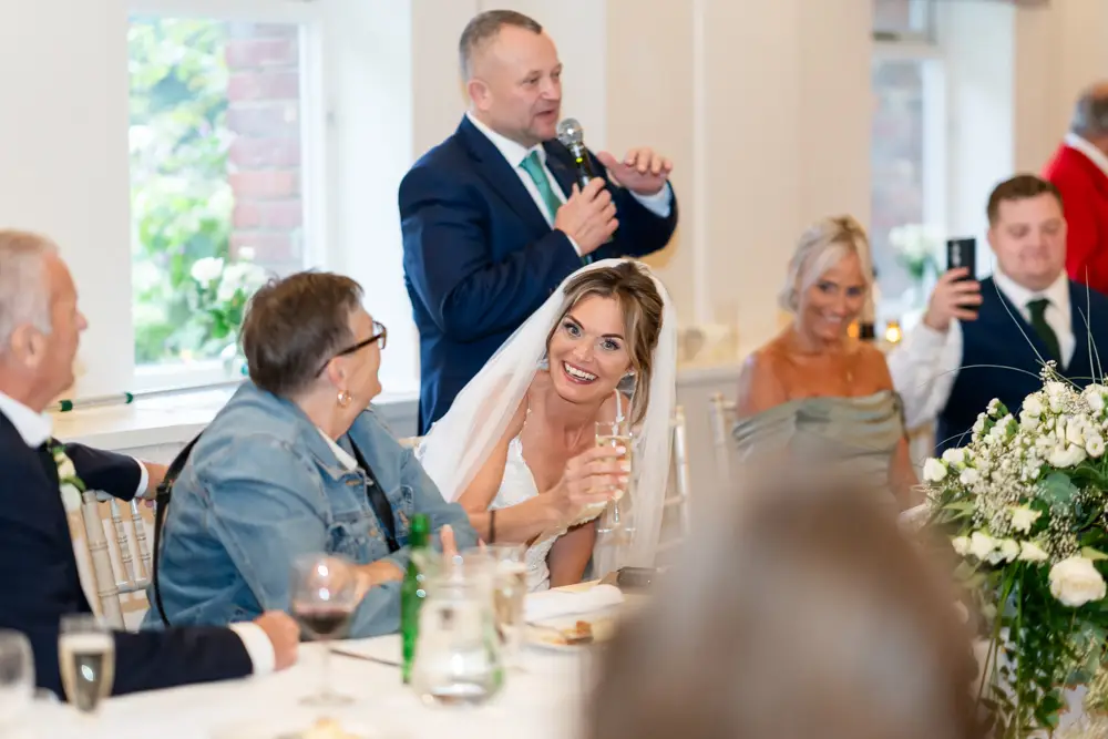 Stoke Place wedding photographer. bride laughing at groom's speech.