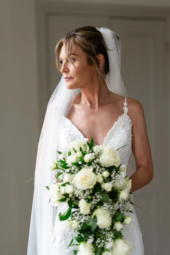 Stoke Place wedding photographer. Bride looks out of window in Alexandra suite.