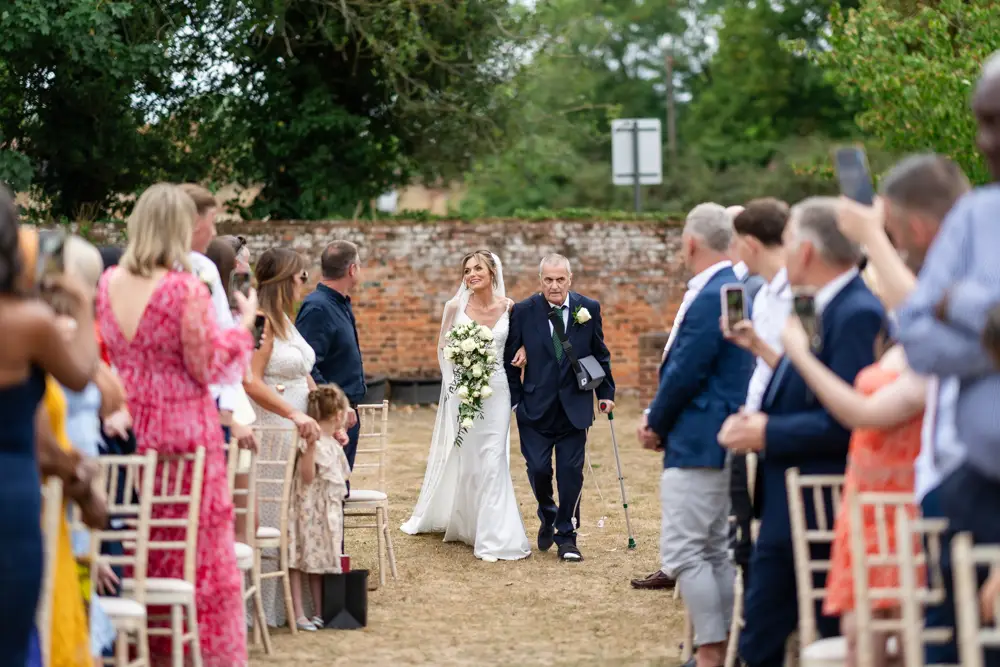 Stoke Place wedding photographer. Bride arriving for outdoor ceremony with her father.