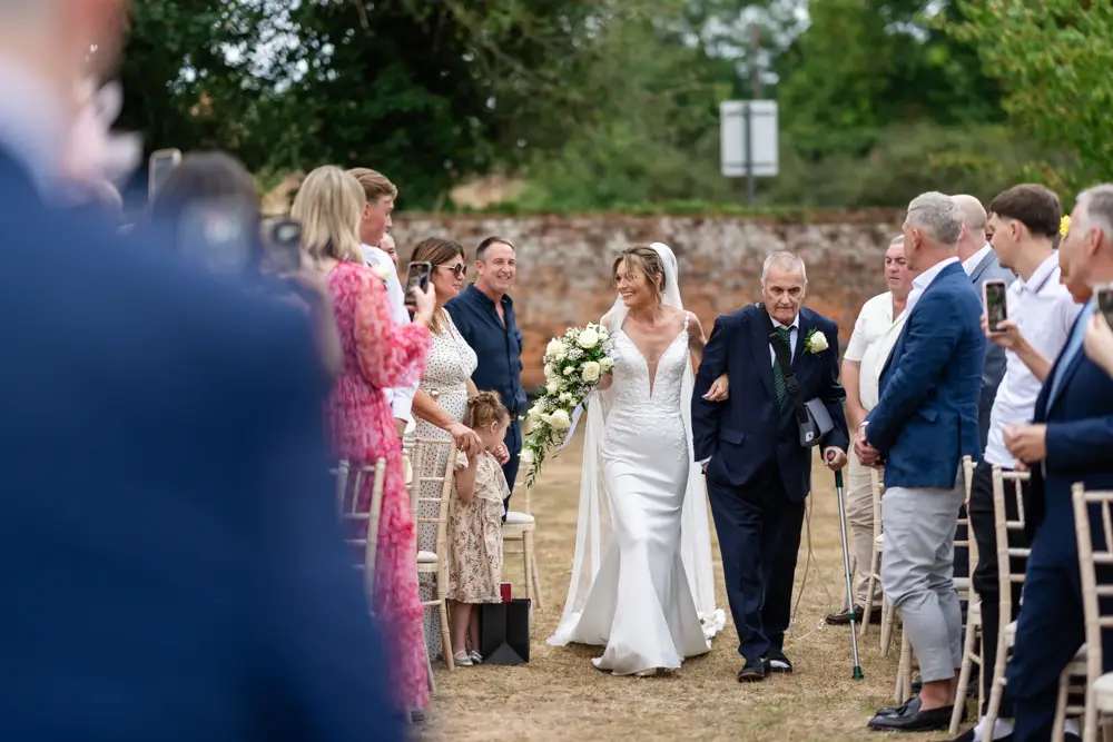Stoke Place wedding photographer. Bride arriving for outdoor ceremony with her father.