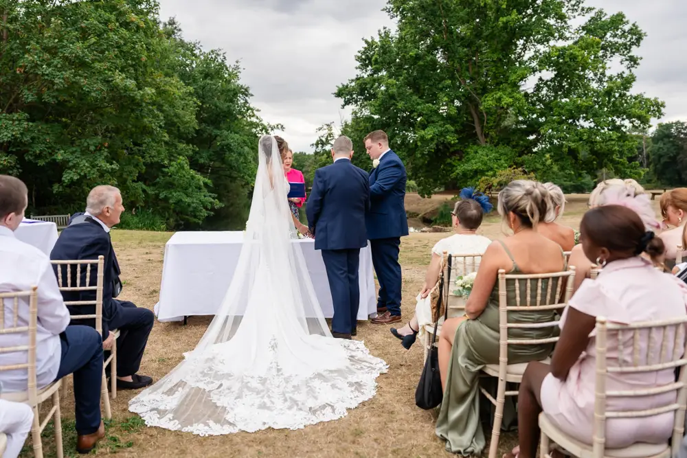 Stoke Place wedding photographer. Bride and groom exchange rings during outdoor ceremony.