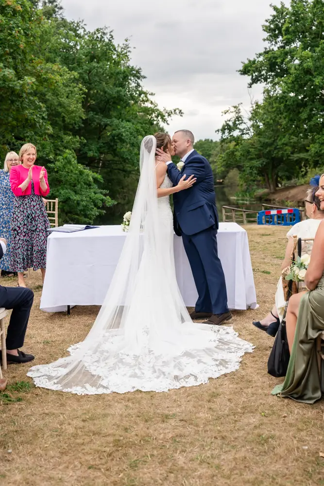 Stoke Place wedding photographer. Bride and groom first kiss at outdoor ceremony.