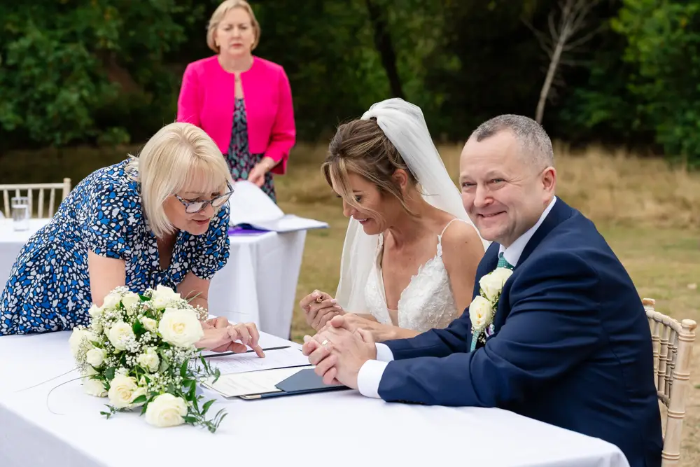 Stoke Place wedding photographer. Bride and groom signing register.