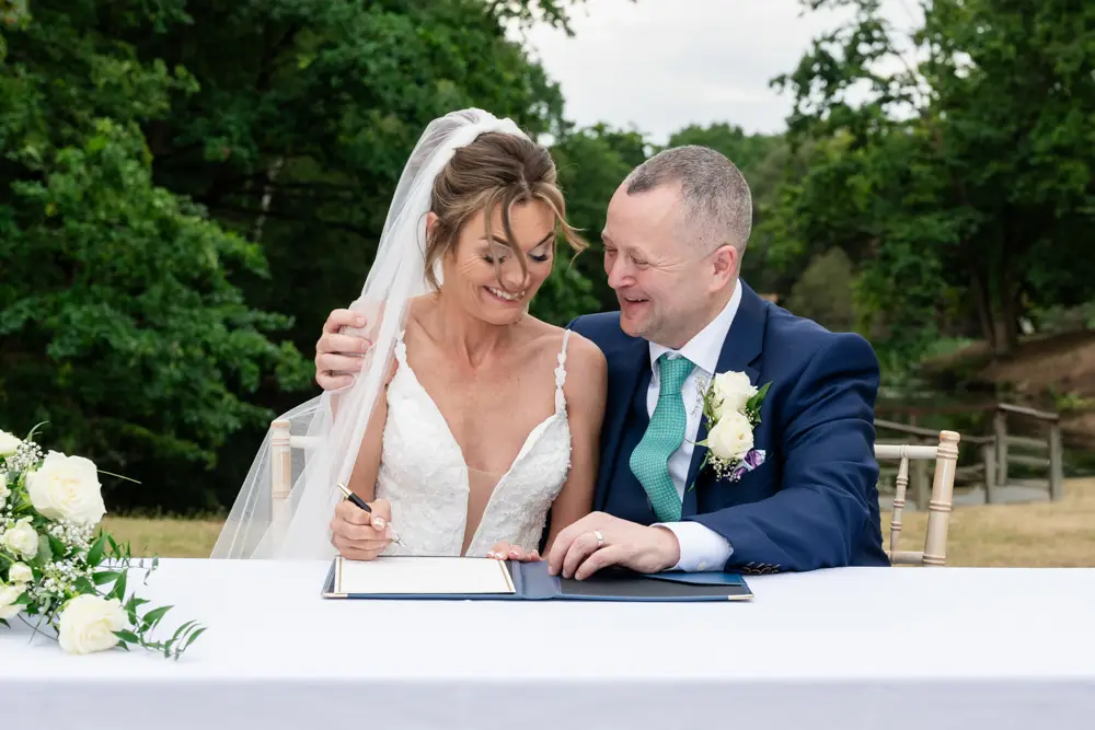 Stoke Place wedding photographer. Bride and groom laughing about mockup signing.