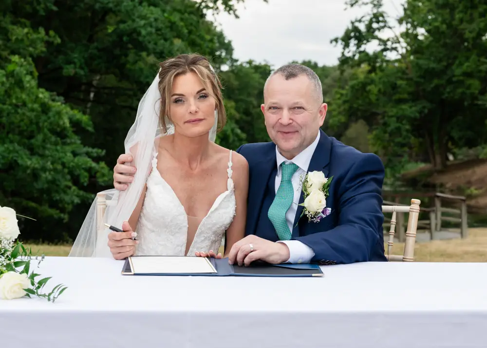 Stoke Place wedding photographer. Bride and groom laughing about mockup signing.
