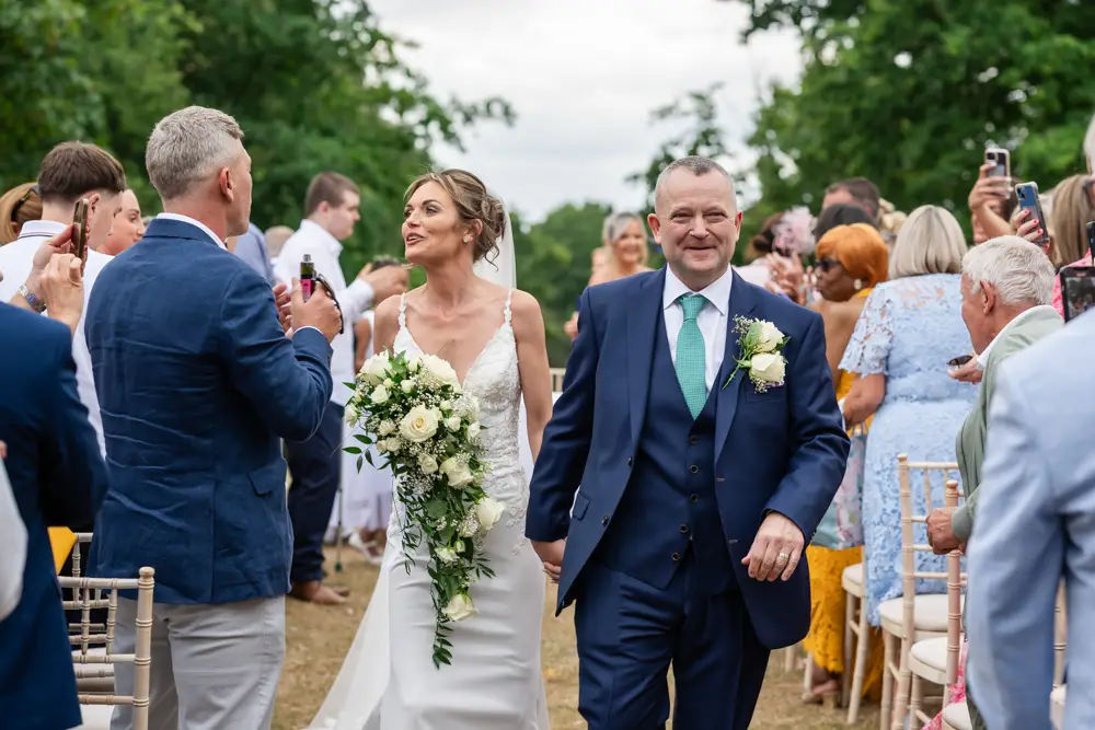 Stoke Place wedding photographer. Bride and groom leaving outdoor wedding ceremony.