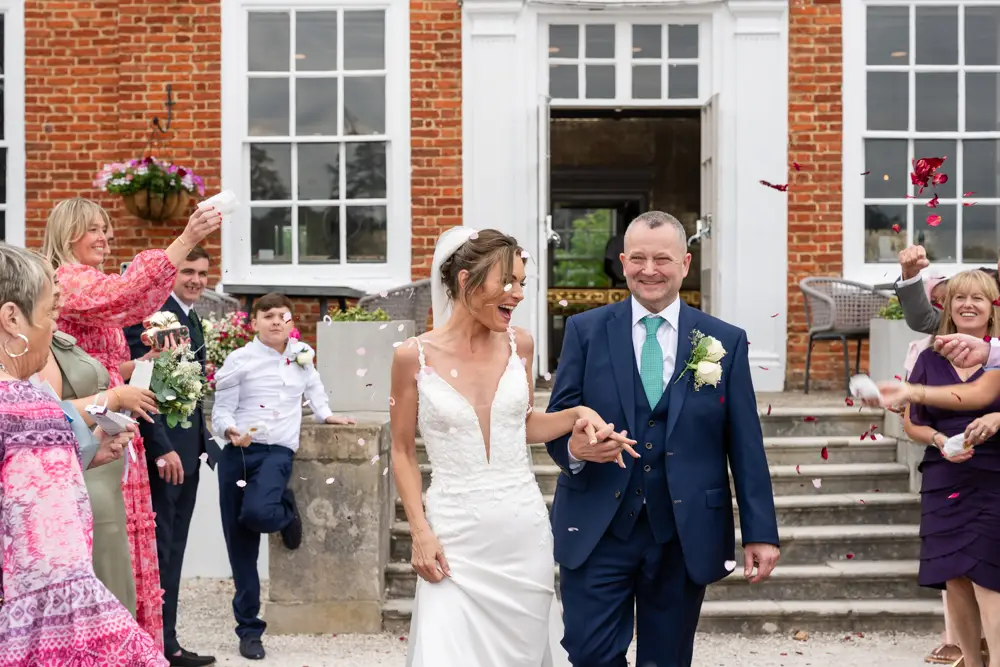 Stoke Place wedding photographer. Bride and groom in confetti tunnel.