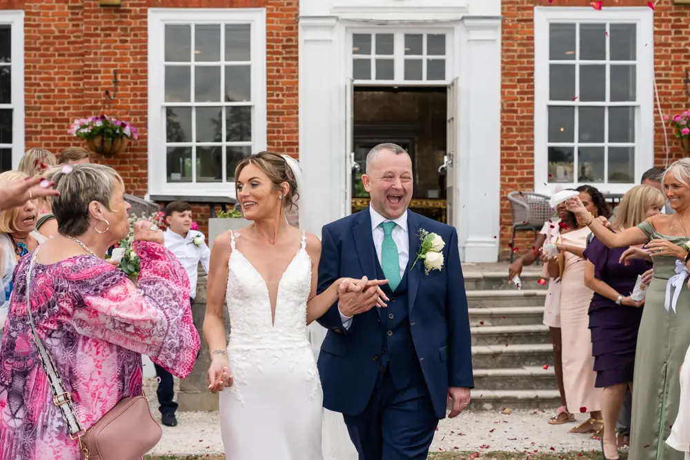 Stoke Place wedding photographer. Bride and groom in confetti tunnel.