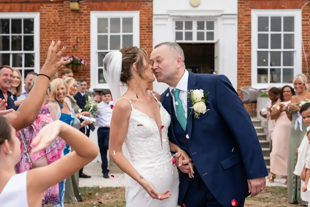 Stoke Place wedding photographer. Bride and groom in confetti tunnel.