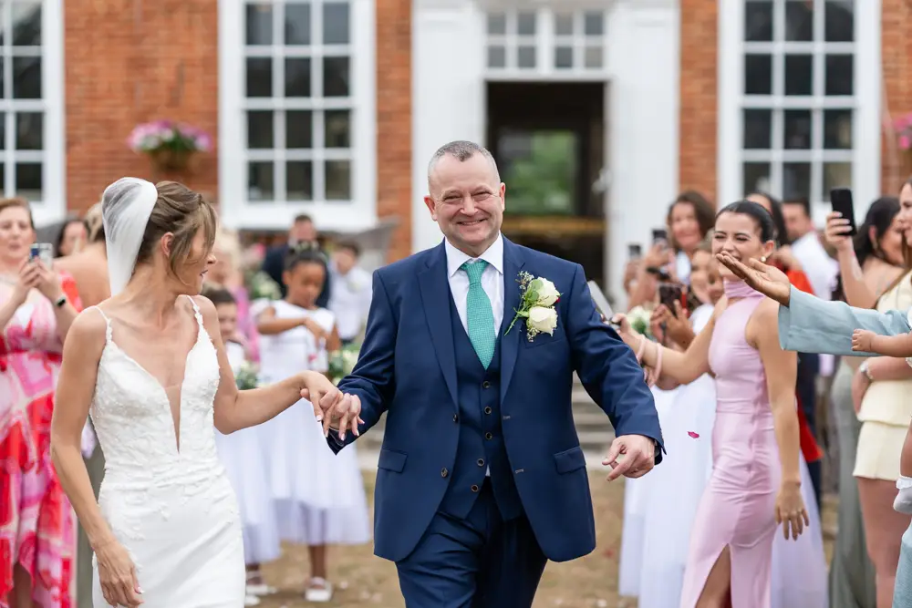 Stoke Place wedding photographer. Bride and groom in confetti tunnel.