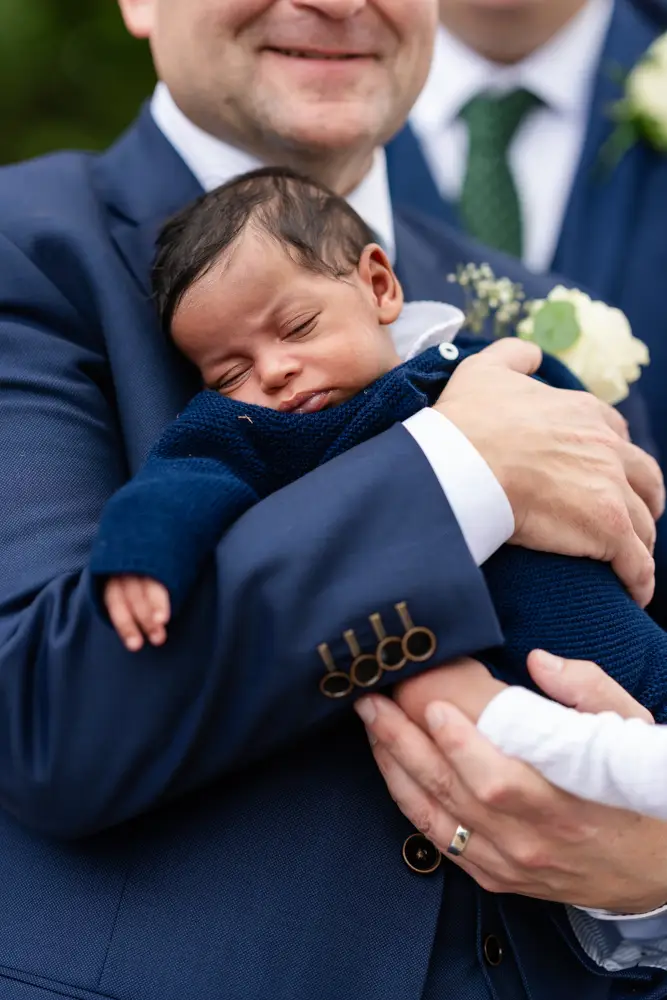 Stoke Place wedding photographer. Groom with new born baby