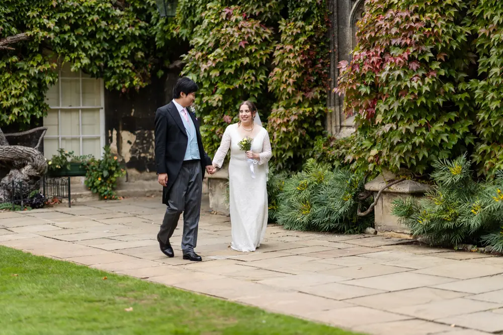 Bride and groom walking in the front quad of Lincoln college Oxford. Lincoln College Oxford wedding photography .