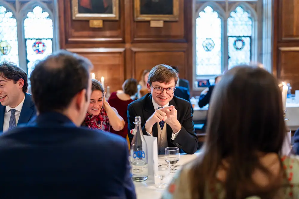 Lincoln College Oxford wedding photographer. Wedding guests chat during wedding breakfast in the dining room.