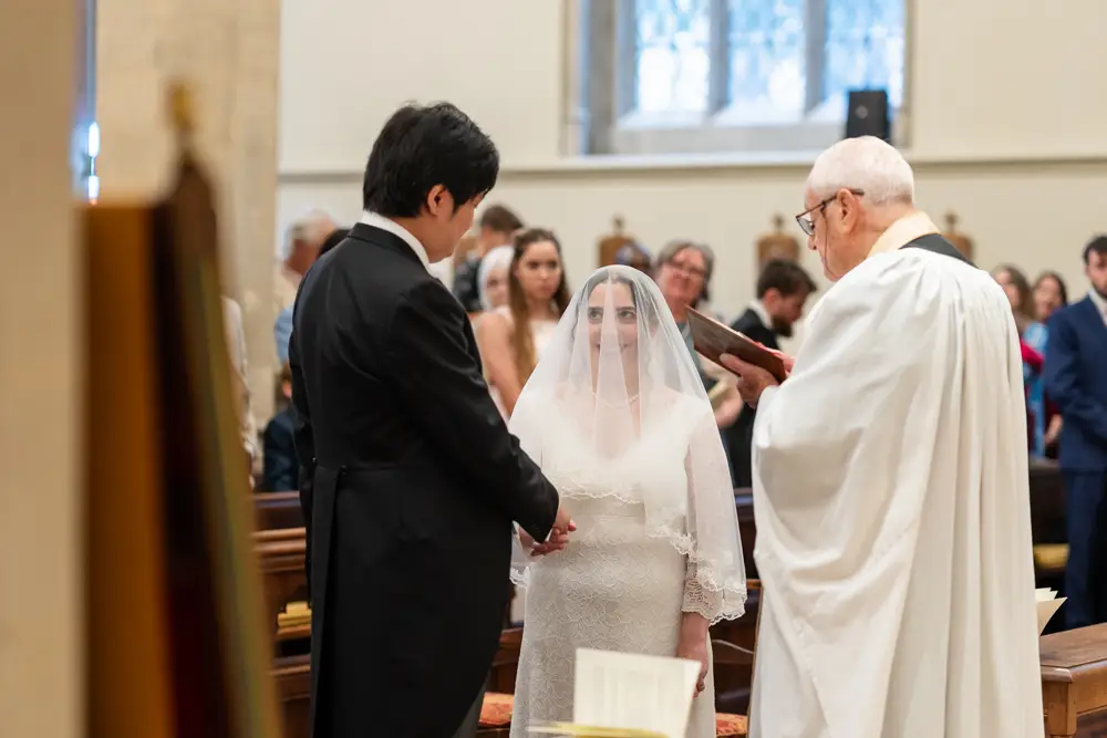 St Mary Magdalen Oxford Wedding Photographer. Bride looks at her groom as he recites wedding vows.