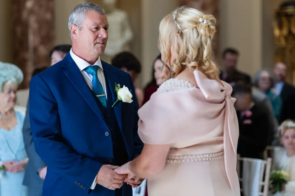 Stowe House wedding photographer. Bride and groom exchange vows during wedding ceremony in the marble hall.