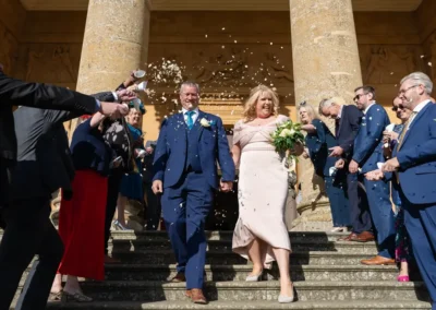 Stowe House wedding photographer. Bride and groom in confetti on steps of south portico in midday sun