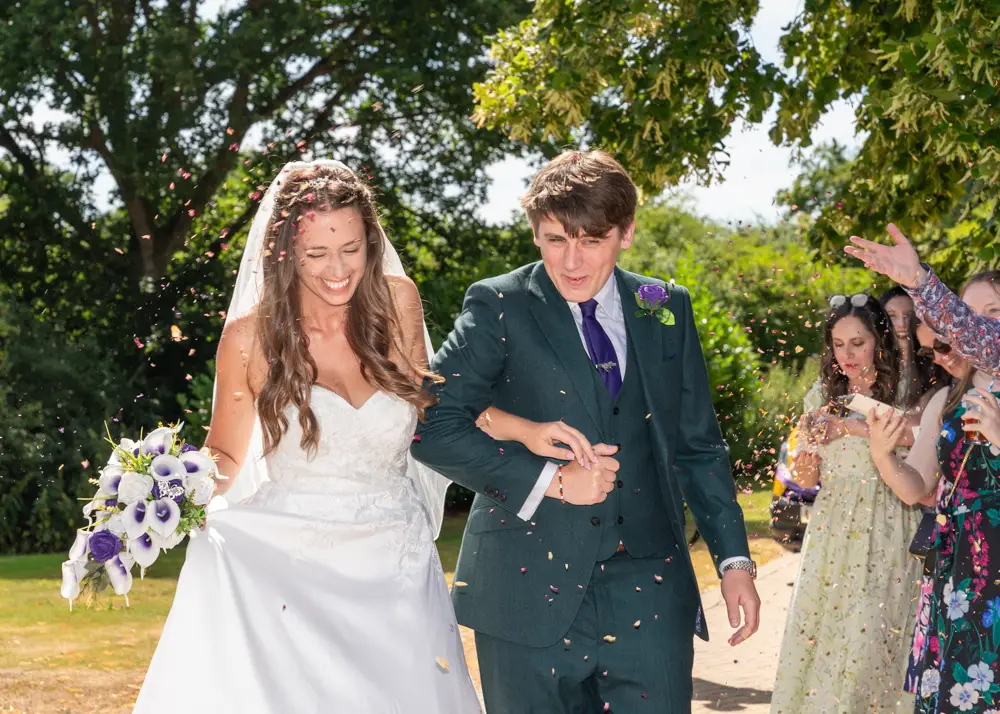 Oxfordshire Wedding Photographer. Bride and groom in confetti tunnel at Dovecote Events.