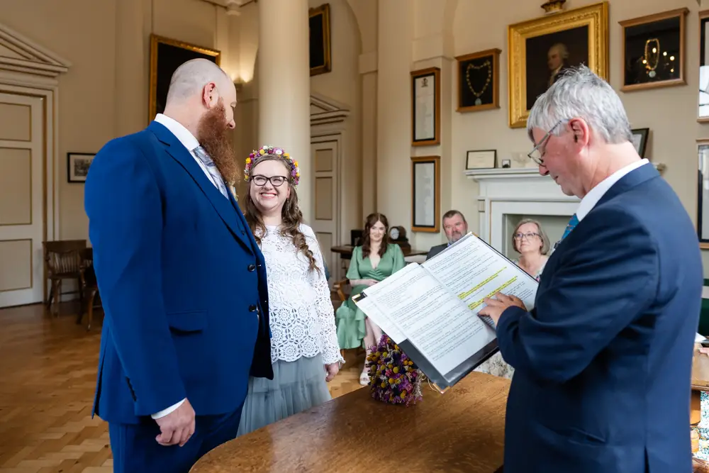 Bride and groom smile at each other during ceremony at Woodstock Town Hall in Oxfordshire