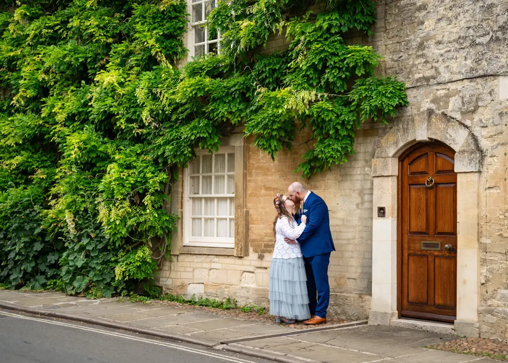 Woodstock wedding photographer. Bride and groom kiss outside Cotswold stone house after their wedding ceremony at Woodstock Town Hall in Oxfordshire.