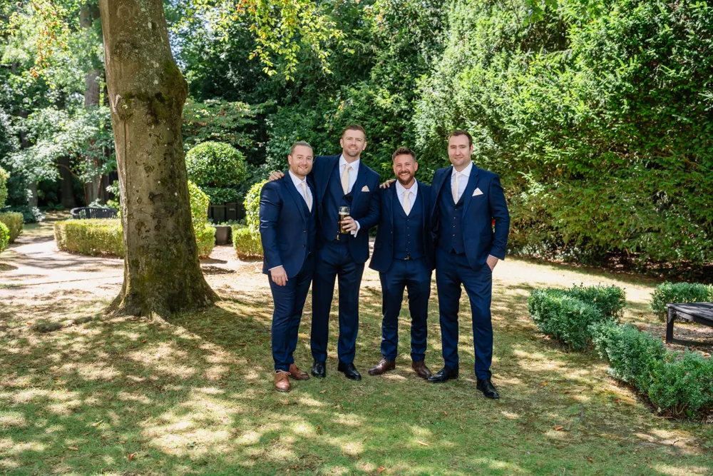 Groom and groomsmen in gardens of Bull hotel before wedding.