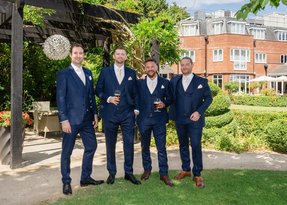 Groom and groomsmen in gardens of Bull hotel before wedding.