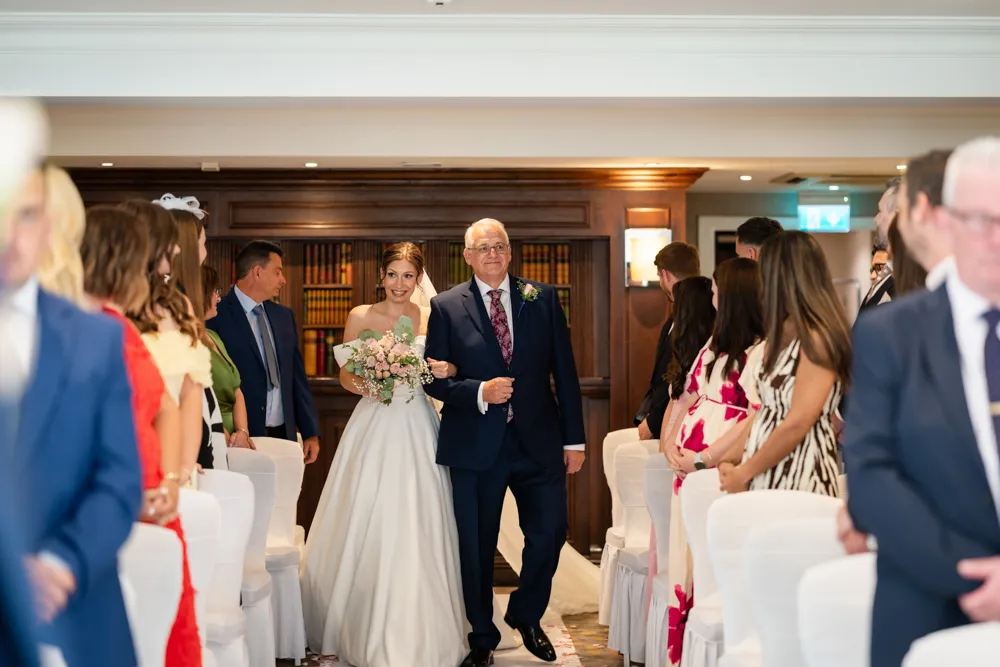 Bride walking down the aisle in Bulstrode Suite for her Bull Hotel wedding ceremony.