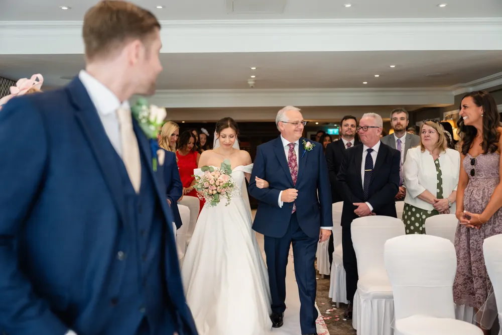 Bride walking down the aisle in Bulstrode Suite for her Bull Hotel wedding ceremony.