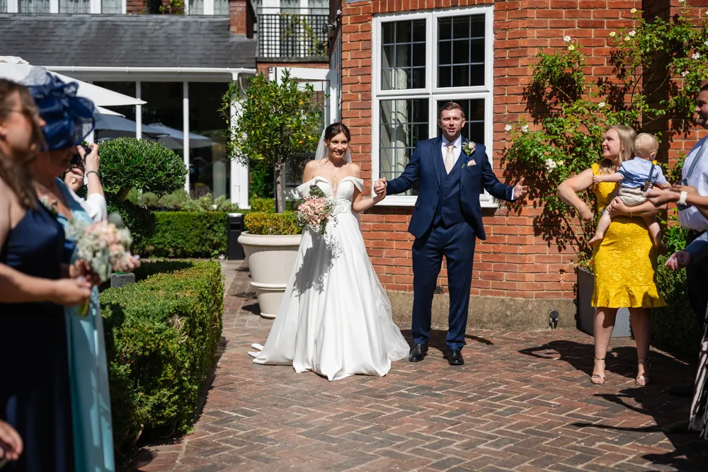 Bride and groom about to walk though confetti in gardens of Bull Hotel in Gerrards Cross.