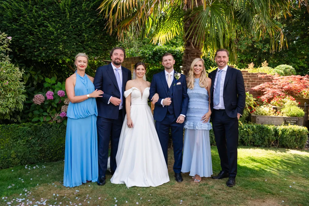Bride and groom with guests in gardens of Bull Hotel in Gerrards Cross.